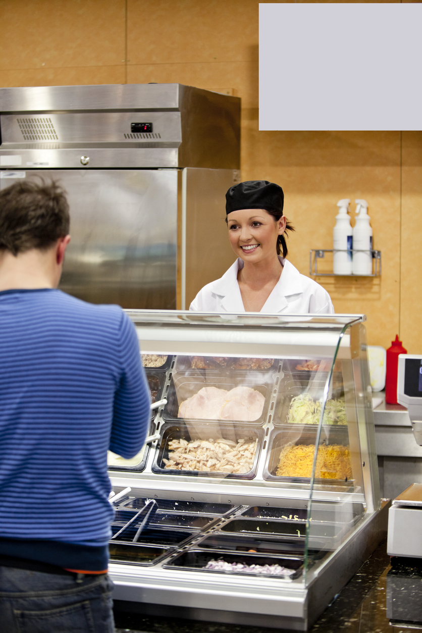 Female cook waiting for a student to choose his lunch in the cafeteria