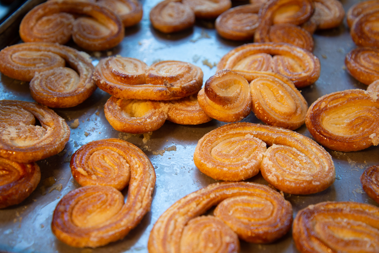 Puff pastry palmiers freshly baked on a tray. High end bakery workshop. Hand made cuisine.